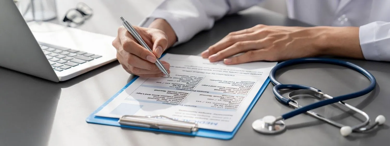 Notes being filled in on a medical form beside a stethoscope